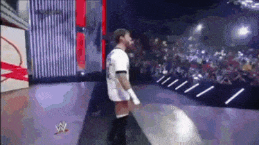 a man is standing on a stage in front of a crowd wearing a white shirt with the number 23 on it .