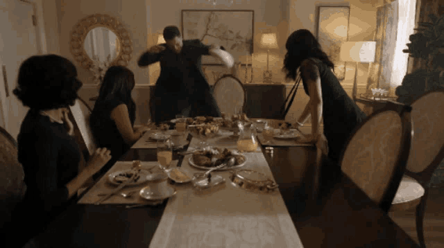 a group of people sitting around a dining table with plates of food on it