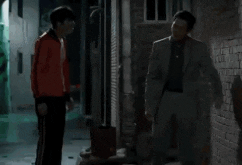 two men standing next to each other in a dark room