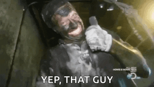 a man with black paint on his face is holding a microphone and saying yep , that guy .