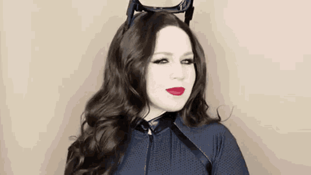 a woman in a catwoman costume is wearing a cat ears headband .