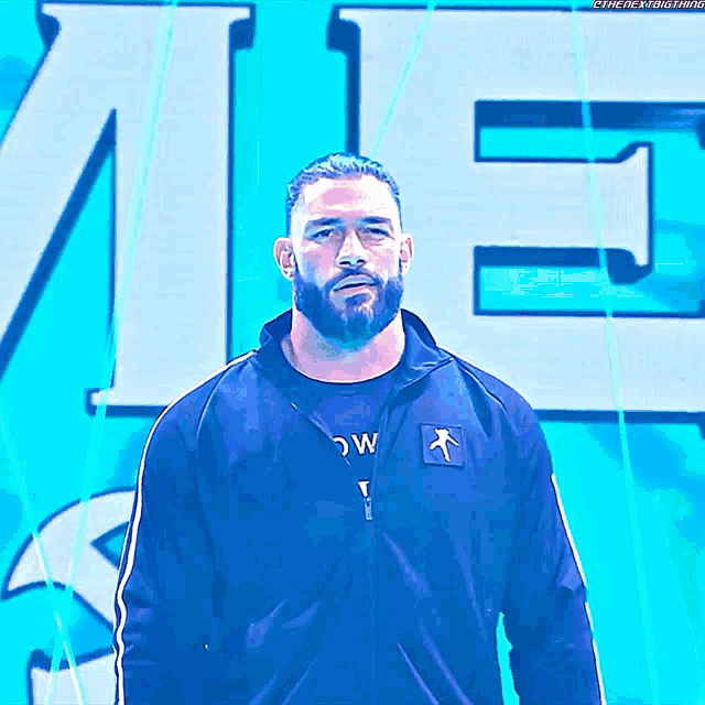 a man with a beard is wearing a blue jacket with the letter e on the back