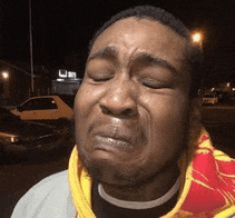 a man wearing a yellow and red scarf is crying with his eyes closed