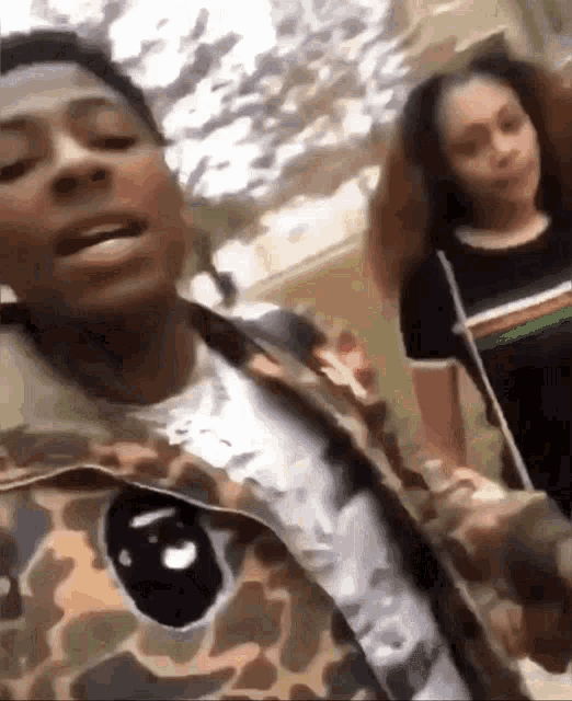 a man in a camo jacket is standing next to a woman in a black shirt .