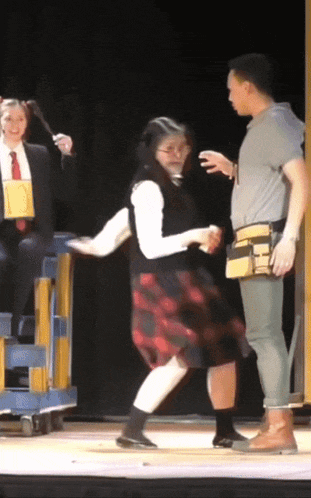 a woman in a plaid skirt is dancing on stage