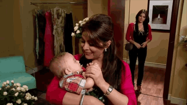 a woman is holding a baby in her arms in a room