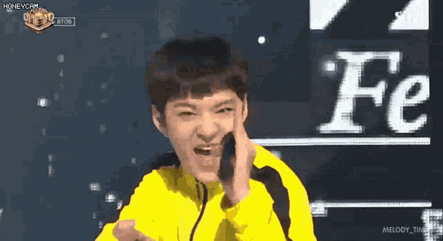 a young man in a yellow jacket is making a funny face in front of the letter fe