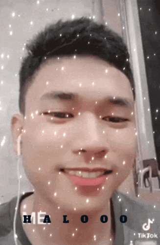 a young man wearing ear buds is smiling and has a tiktok logo on his face