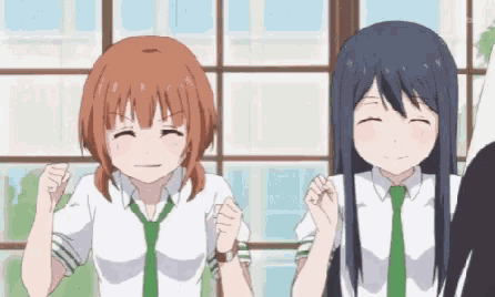 two anime girls are standing next to each other in front of a window with their fists in the air .