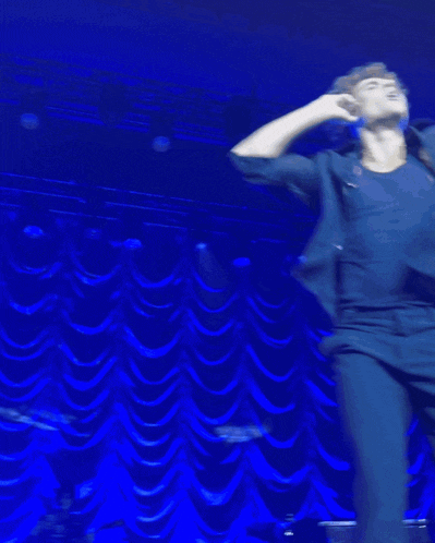 a man singing into a microphone with his arms outstretched