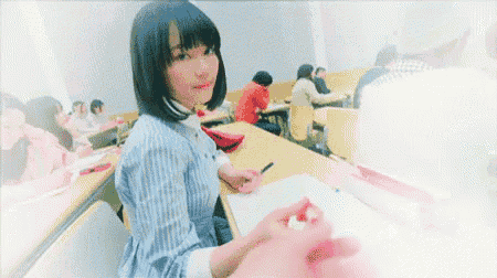 a woman is sitting at a desk in a classroom looking at the camera .