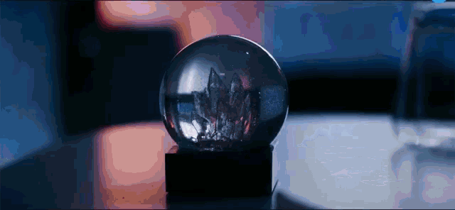 a snow globe on a table with a glass of water in the background