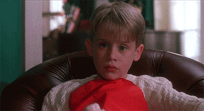 a young boy is sitting in a chair wearing a santa hat and a red scarf around his neck .