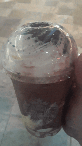 a person is holding a cup of starbucks coffee with whipped cream on top