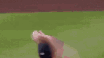 a baseball player in a green shirt and white pants is catching a ball on a baseball field .