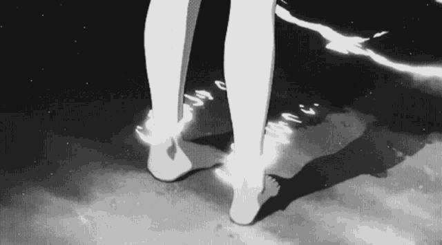 a black and white drawing of a person 's feet standing on a beach