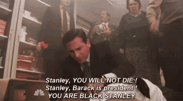 a man in a suit and tie is laying on the floor with a dog and says stanley you will not die
