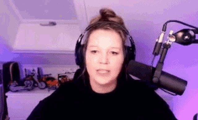a woman wearing headphones and a microphone is sitting in front of a microphone in a room .
