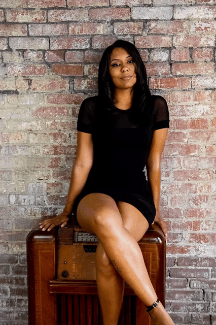 a woman in a black dress is sitting on a radio