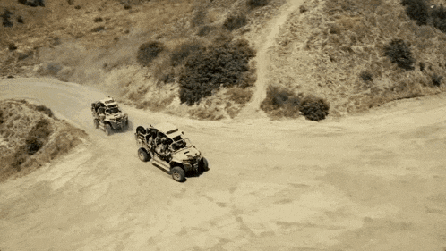two atvs are going down a dirt road
