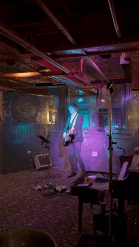a man playing a guitar on stage in a dark room