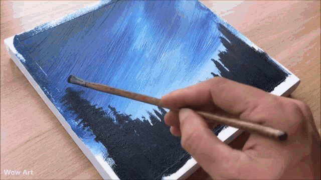 a person is painting a picture with wow art written on the bottom right