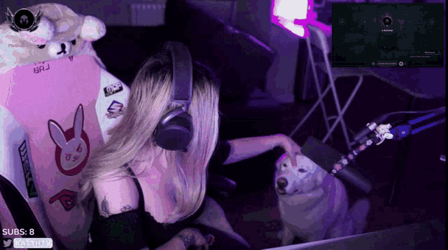 a woman wearing headphones is playing a video game with a dog in the background