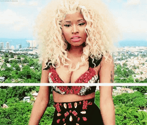 a woman with blonde curly hair is standing in front of a city and trees .