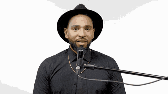 a man singing into a microphone wearing a black hat