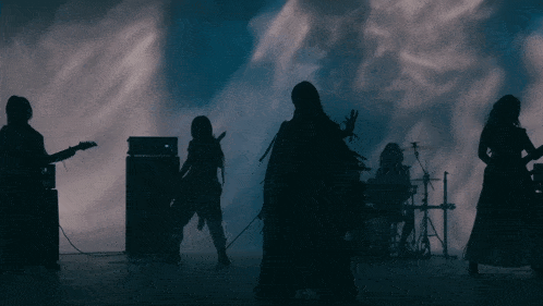 a group of people playing instruments on a stage in the dark