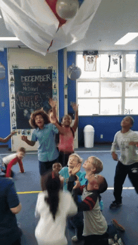 a group of children are playing in a room with a blackboard that says december