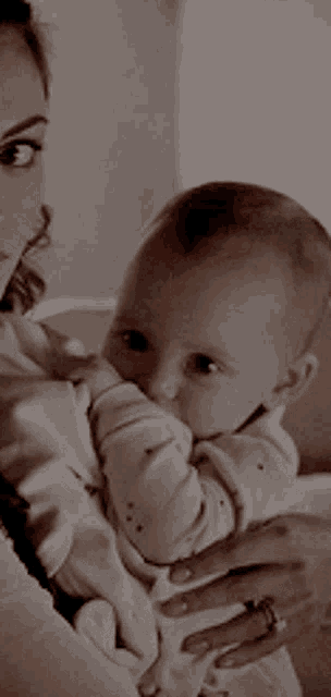 a woman is holding a baby in her arms and the baby is eating from her hand