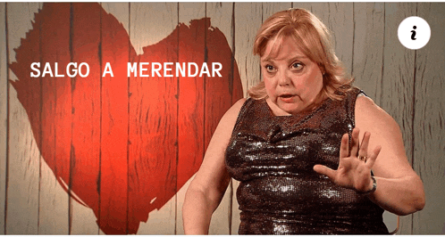 a woman stands in front of a red heart with the words salgo a merendar above her