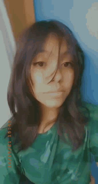 the girl is wearing a green shirt and taking a selfie .