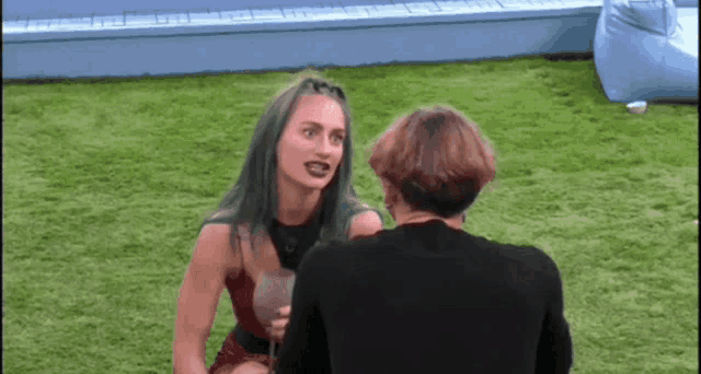 a man and a woman are sitting on the grass and talking