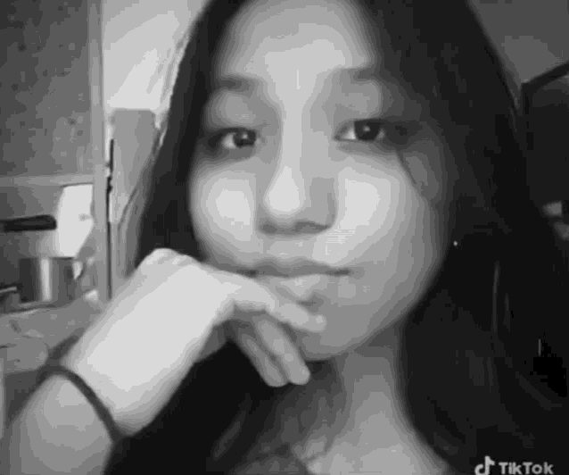 a black and white photo of a young woman with tiktok written on the bottom