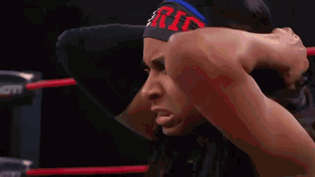 a female wrestler is standing in a wrestling ring with her hands on her head .