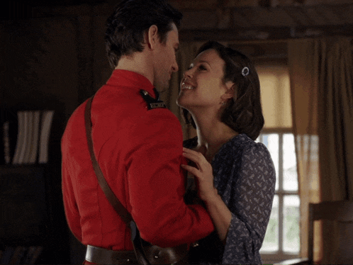 a man in a red uniform kisses a woman who is wearing a blue shirt with the name andrew coppin on the bottom