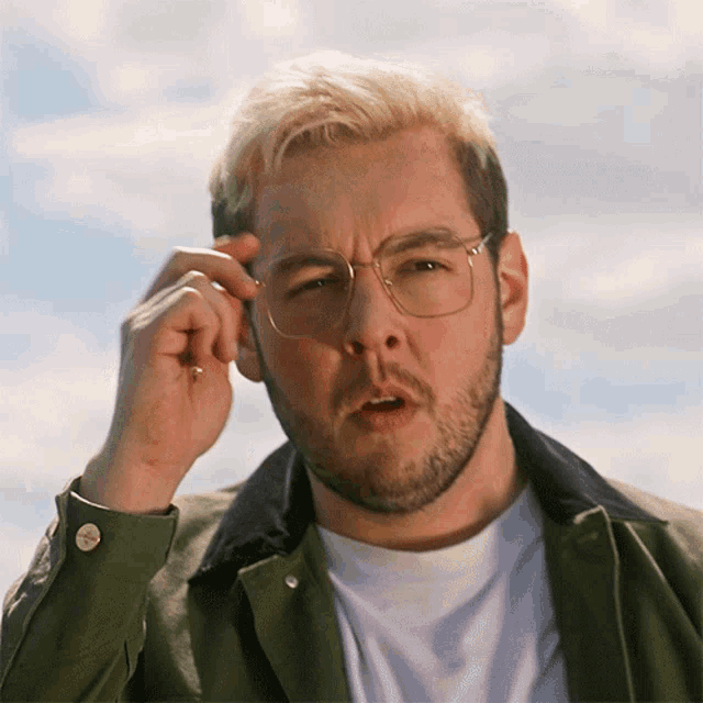 a man wearing glasses and a green jacket is looking at something