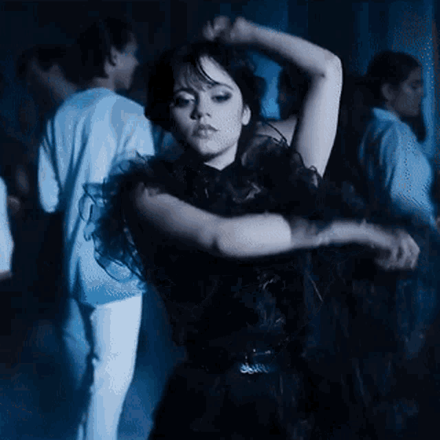 a woman in a black dress is dancing in a club