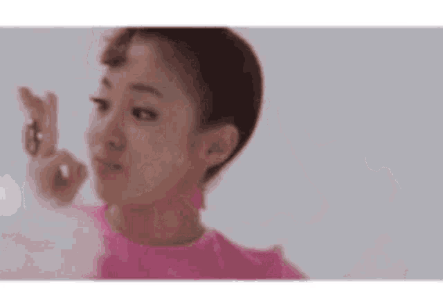 a woman in a pink shirt is making a funny face with her fingers crossed .