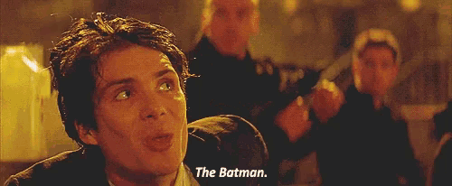 a man in a suit says " the batman " in front of another man