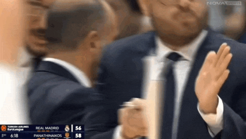 a man in a suit and tie applauds during a basketball game