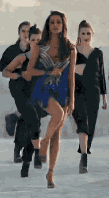 a woman in a blue dress is dancing with a group of women