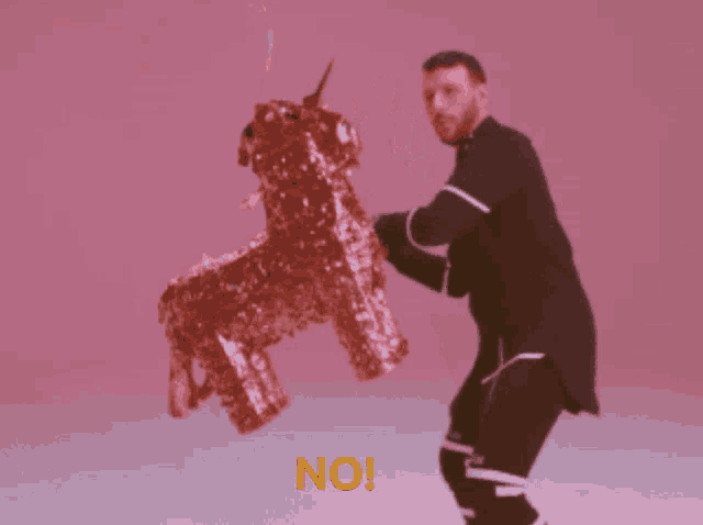 a man holding a piñata with the word no on the bottom right