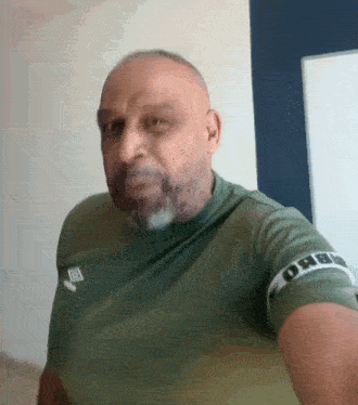 a man with a beard is wearing a green shirt that says urbi on it
