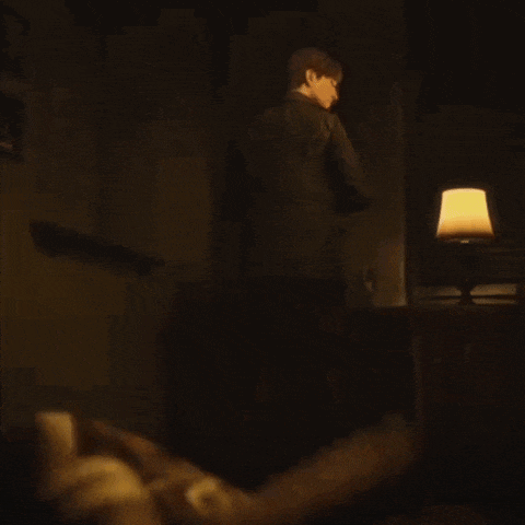 a man is standing in a dark room with a lamp on