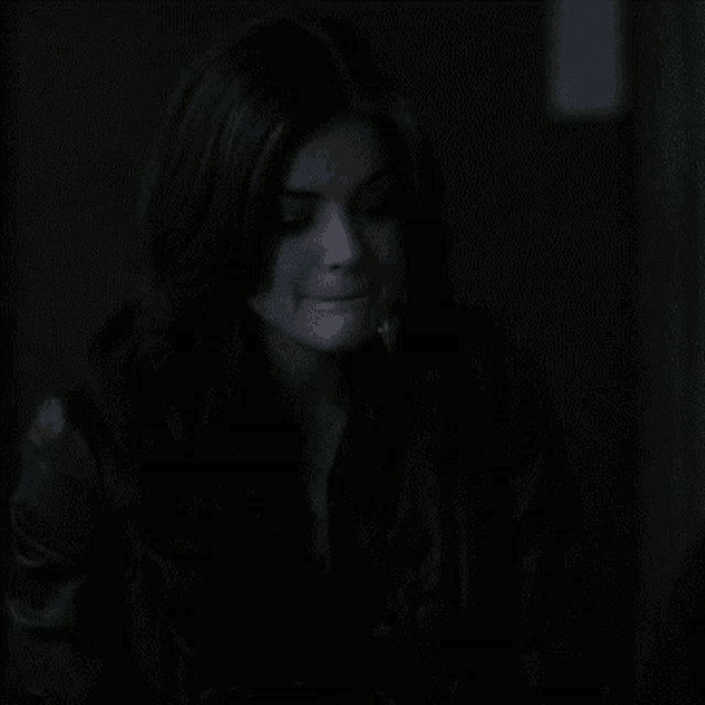 a woman in a dark room is smiling and looking to the side