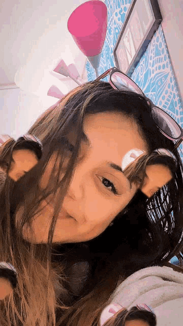a woman wearing sunglasses is taking a selfie in front of a pink lamp