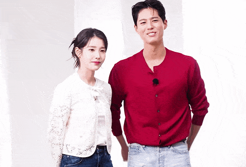 a man in a red sweater stands next to a woman in a white jacket